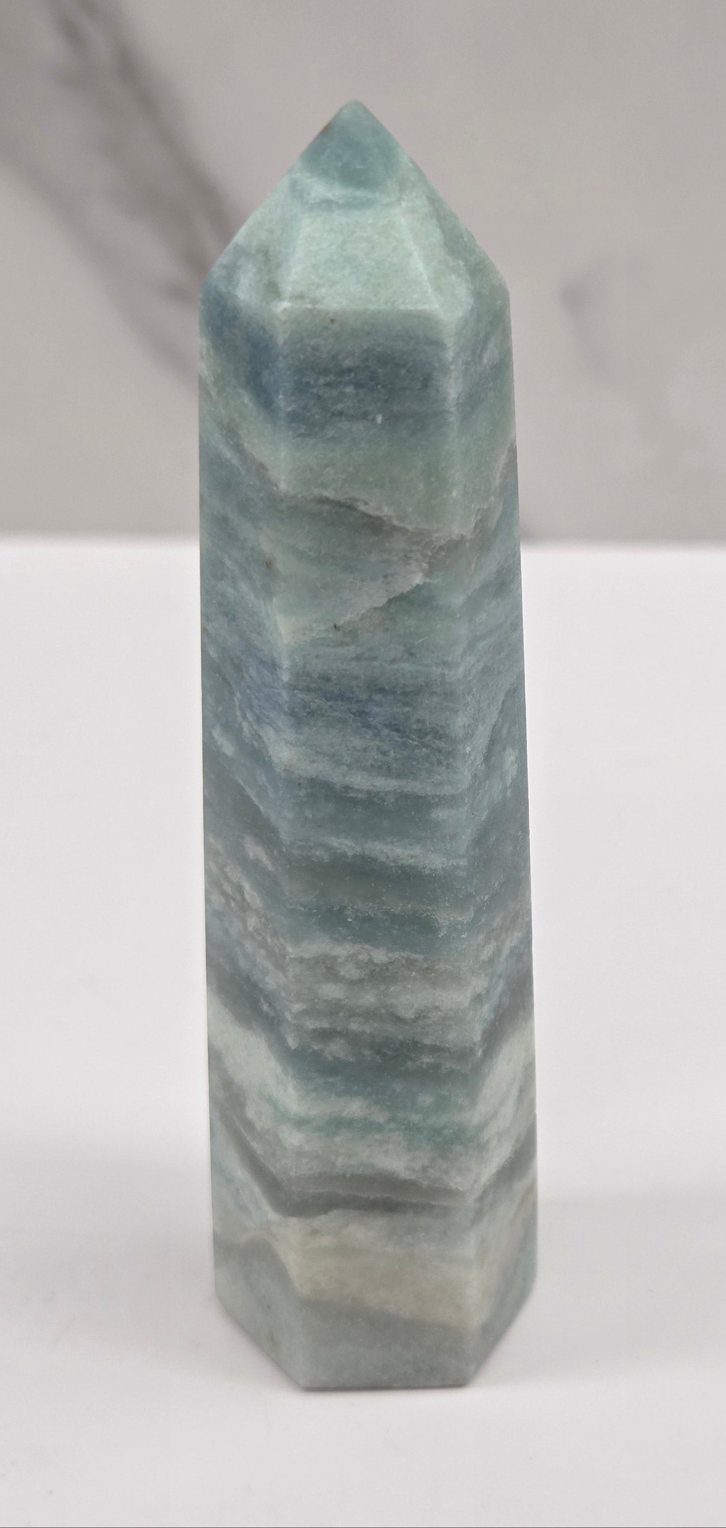 Blue Calcite tower with bands of blue and white on a white background