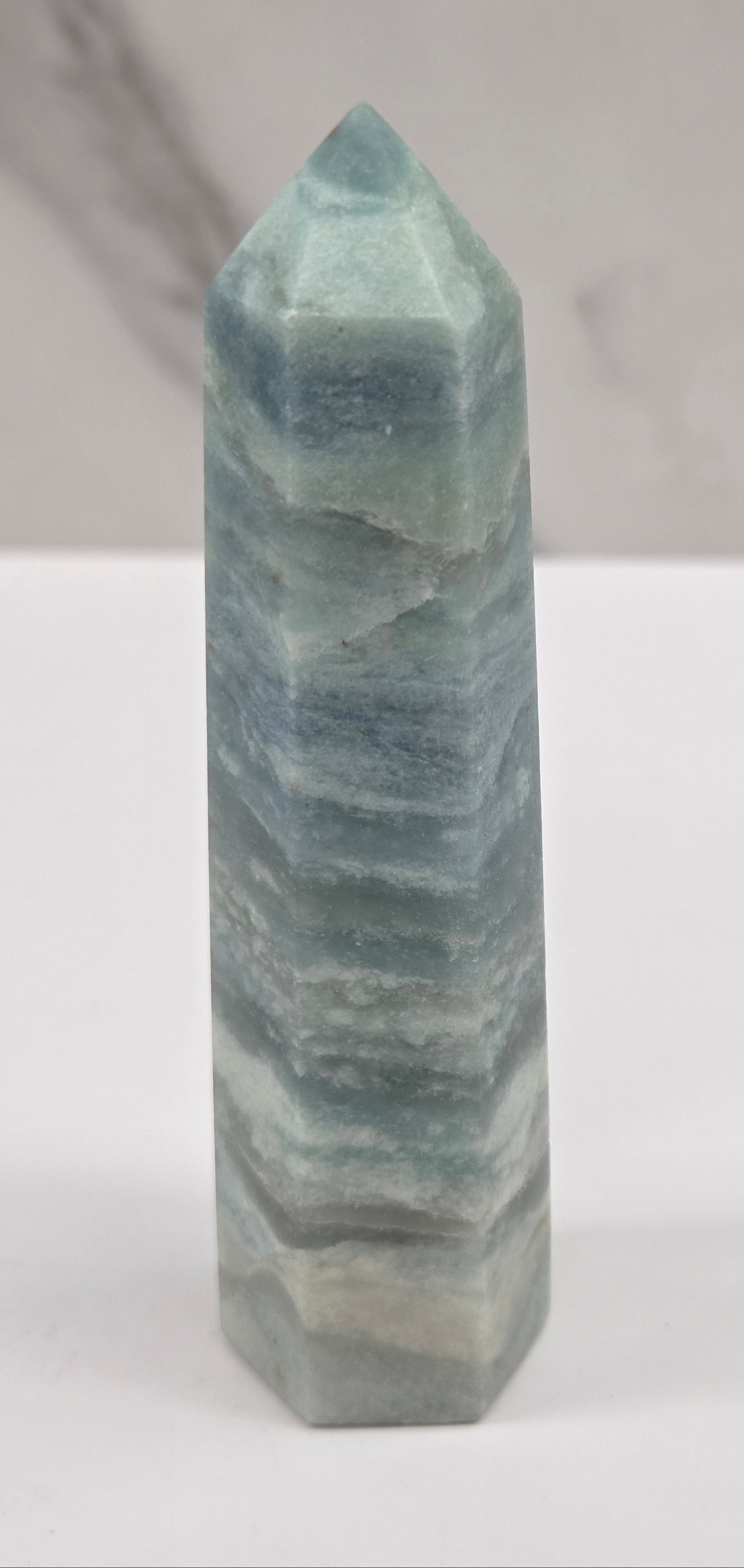 Blue Calcite tower with bands of blue and white on a white background