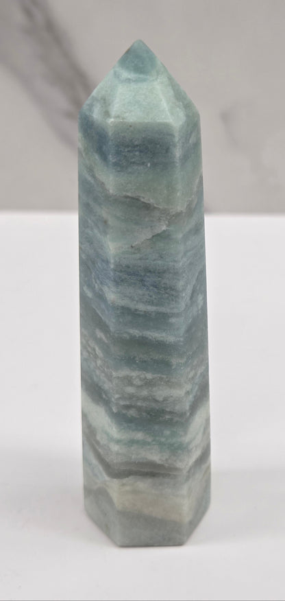 Blue Calcite tower with bands of blue and white on a white background