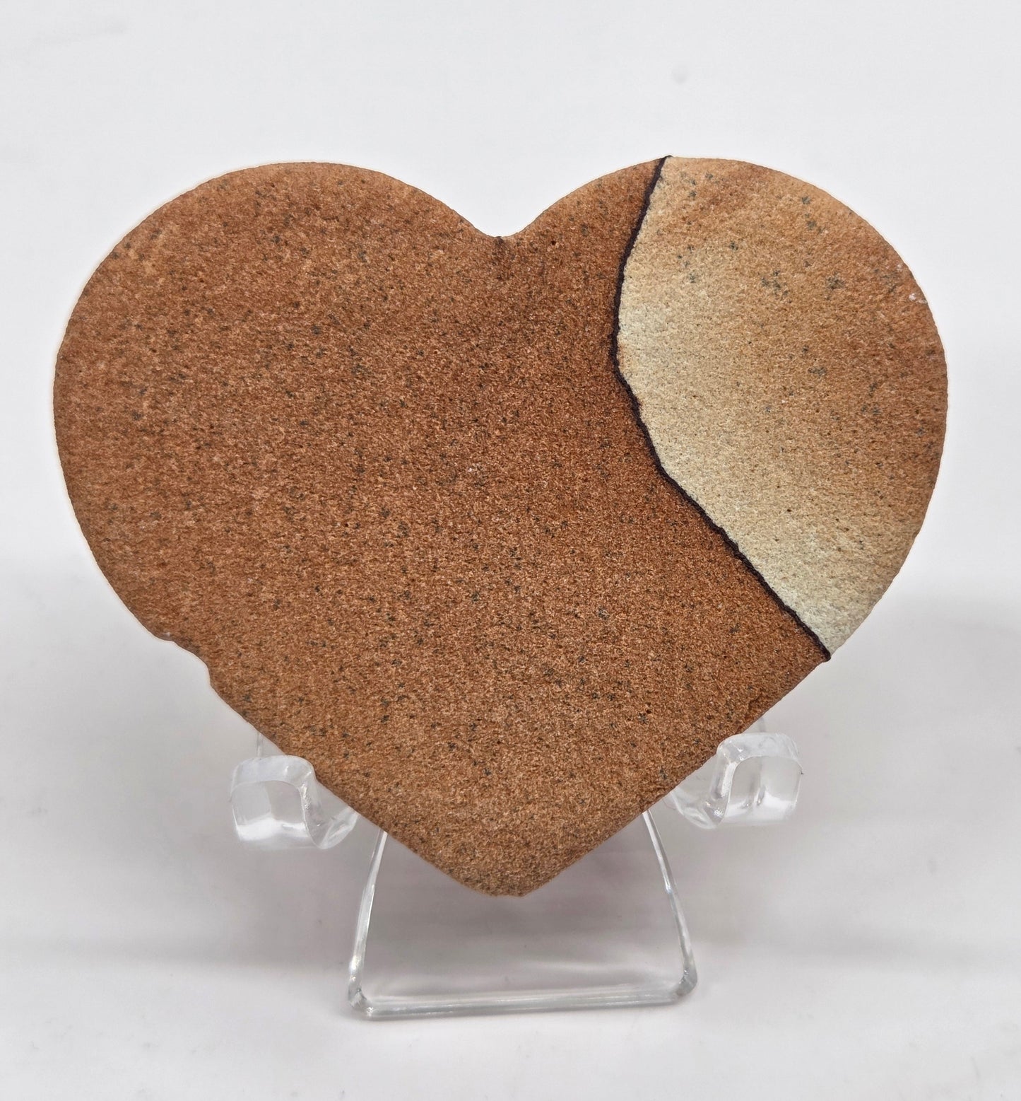 Picture Sandstone brown heart on a clear stand against a white background
