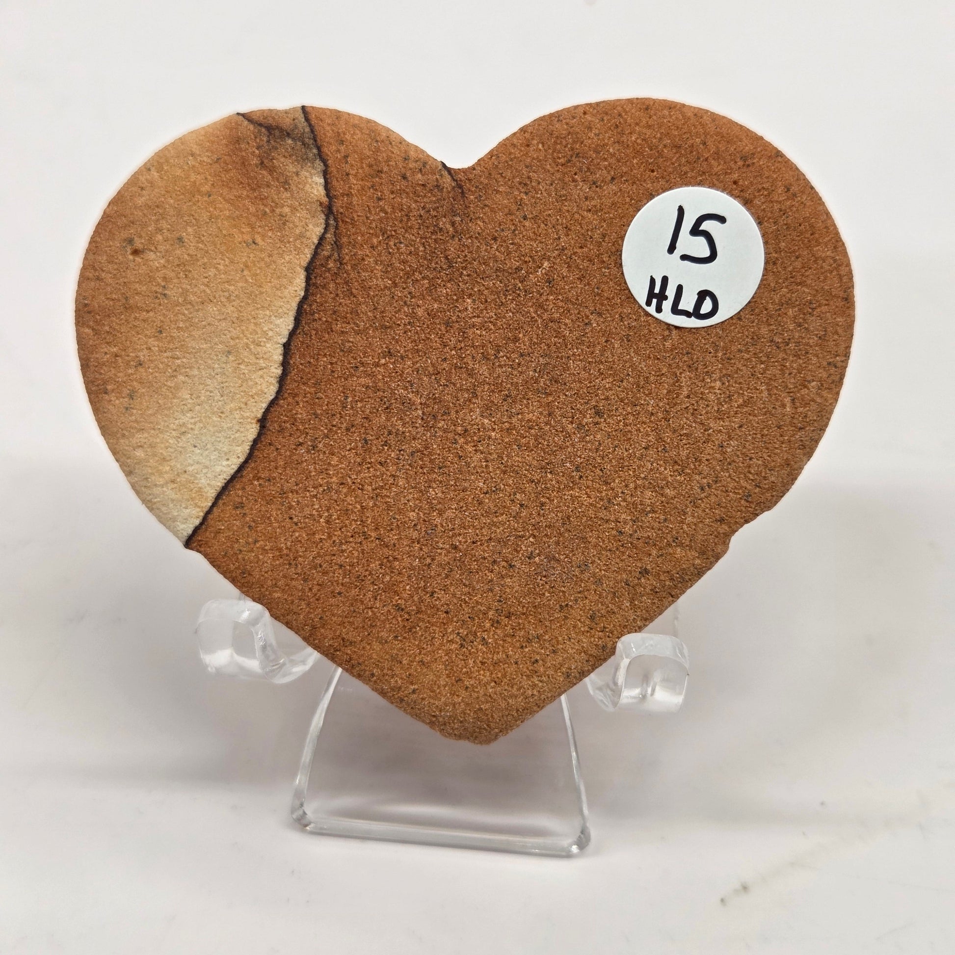 Picture Sandstone brown heart on a clear stand against a white background