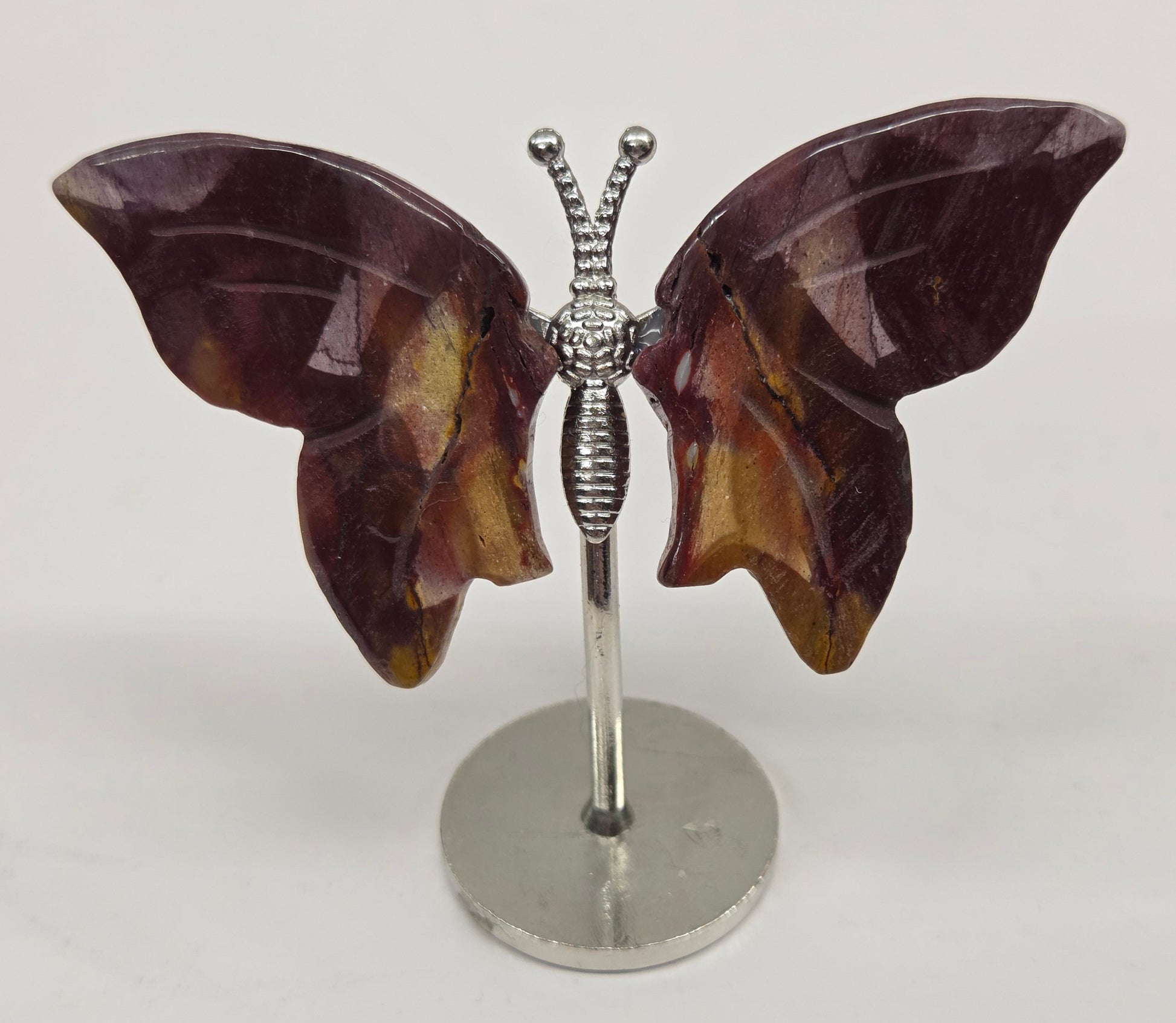 Butterfly-shaped mookaite wings on stands with a marble-like texture against a neutral background