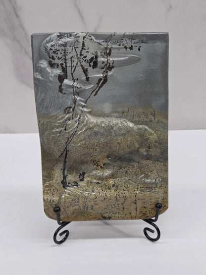 Picture Jasper slab with patterns and a wolf and moon carved into it, on a black stand against a white background