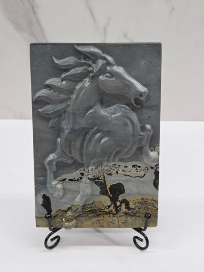 Picture Jasper slab with patterns and a horse carved into it, on a black stand against a white background