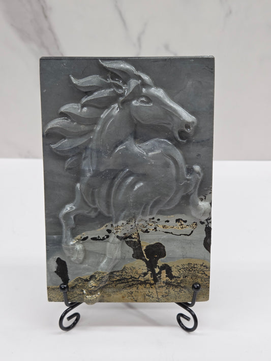 Picture Jasper slab with patterns and a horse carved into it, on a black stand against a white background