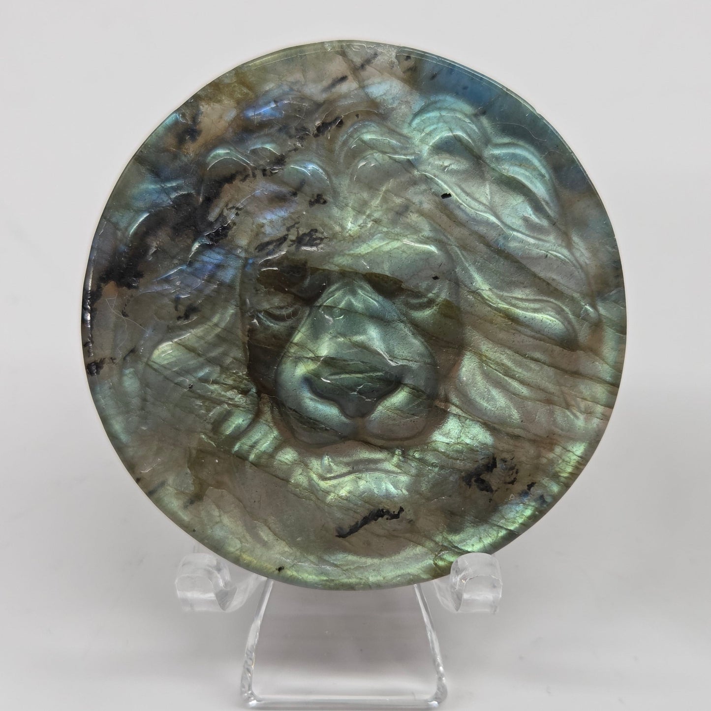 Decorative labradorite coin with a lion carving on a white background