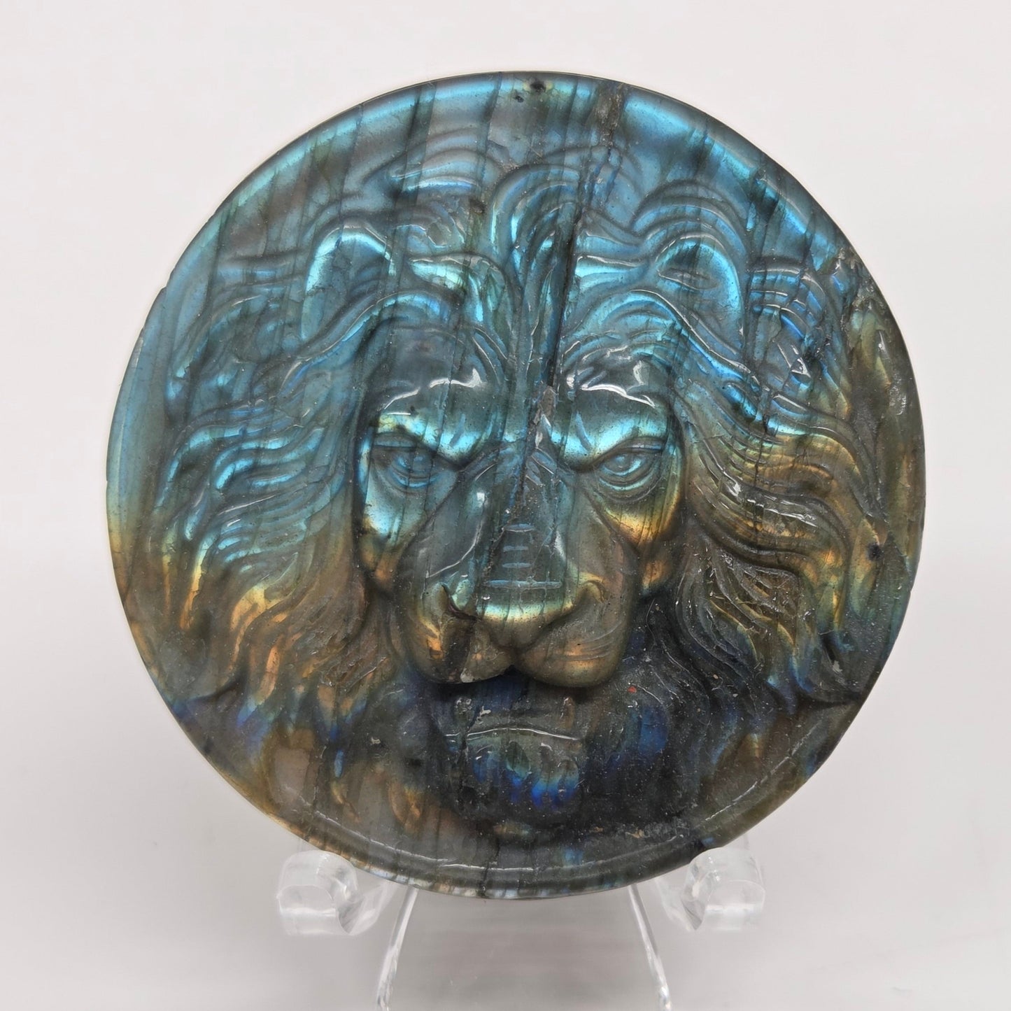 Decorative labradorite coin with a lion carving on a white background