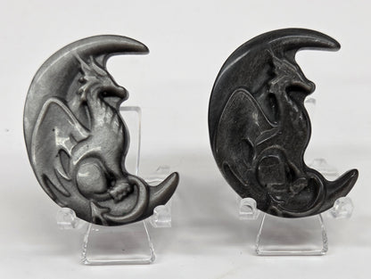 Two silver sheen obsidian dragon-shaped carvings on a white background
