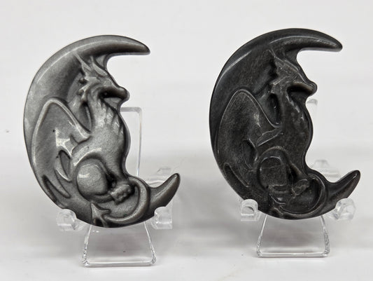 Two silver sheen obsidian dragon-shaped carvings on a white background