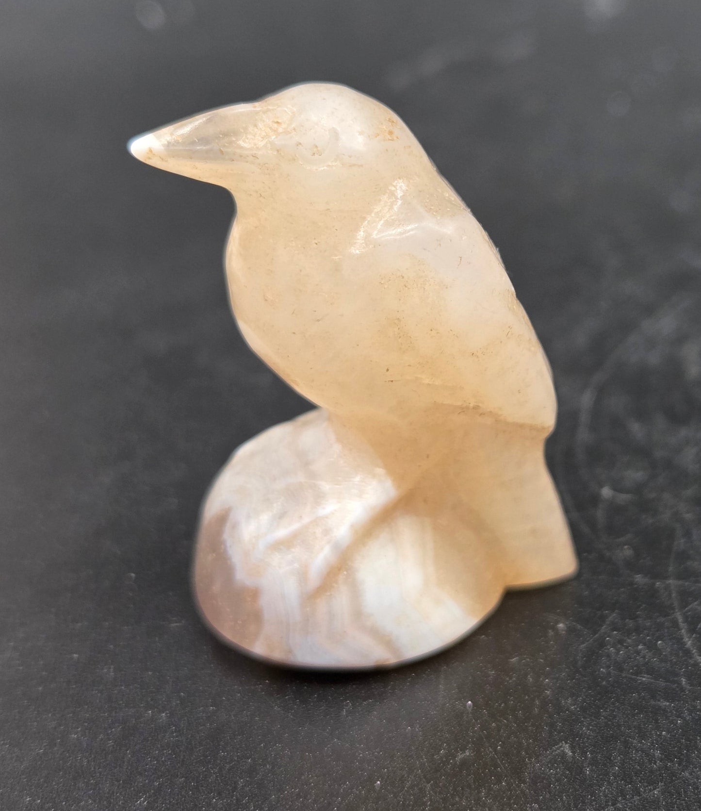 A small carving of a raven made from Moonstone, approximately 1.5 inches tall.