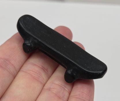 Obsidian skateboard carving being held in a hand against a white background