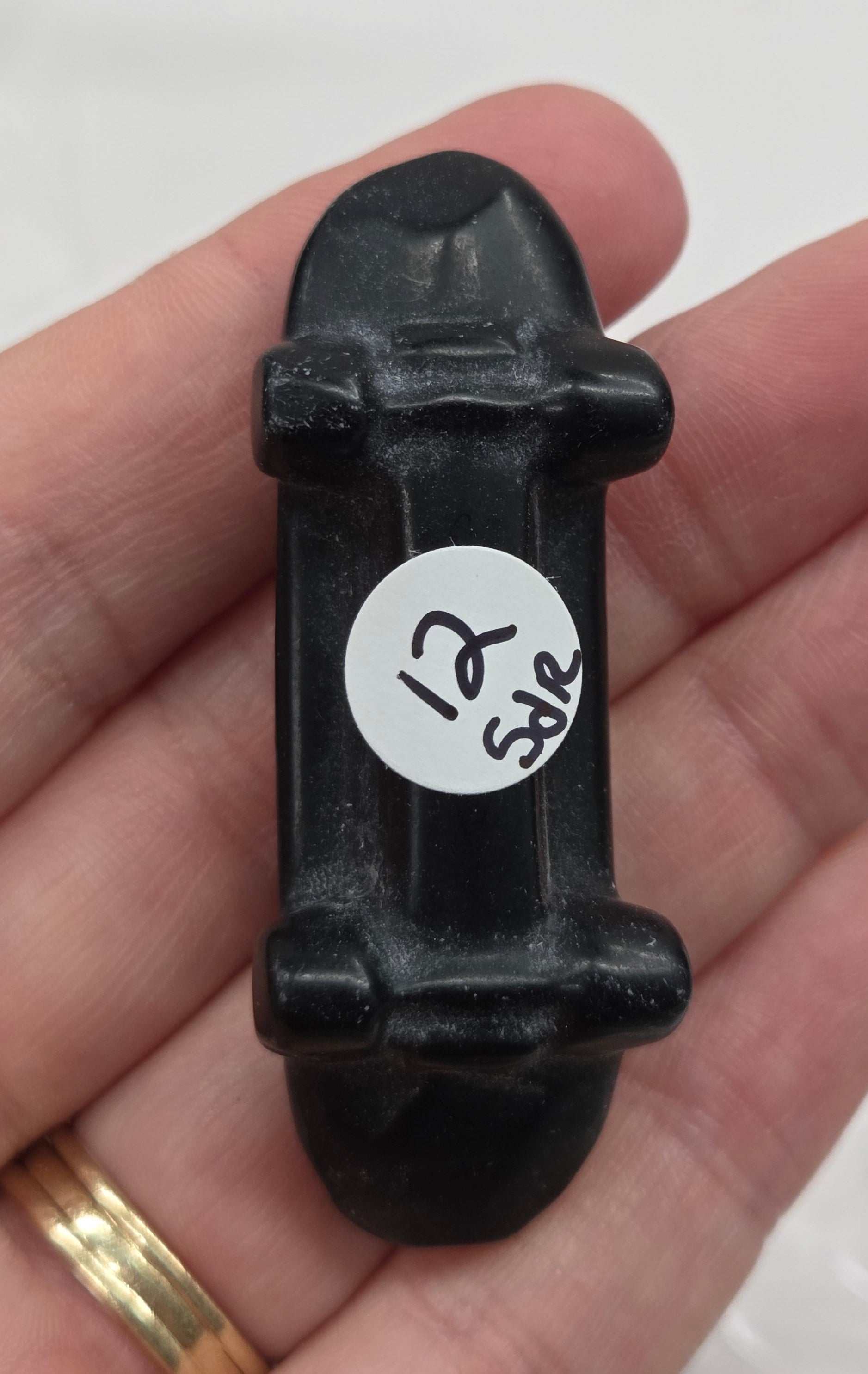 Obsidian skateboard carving being held in a hand against a white background