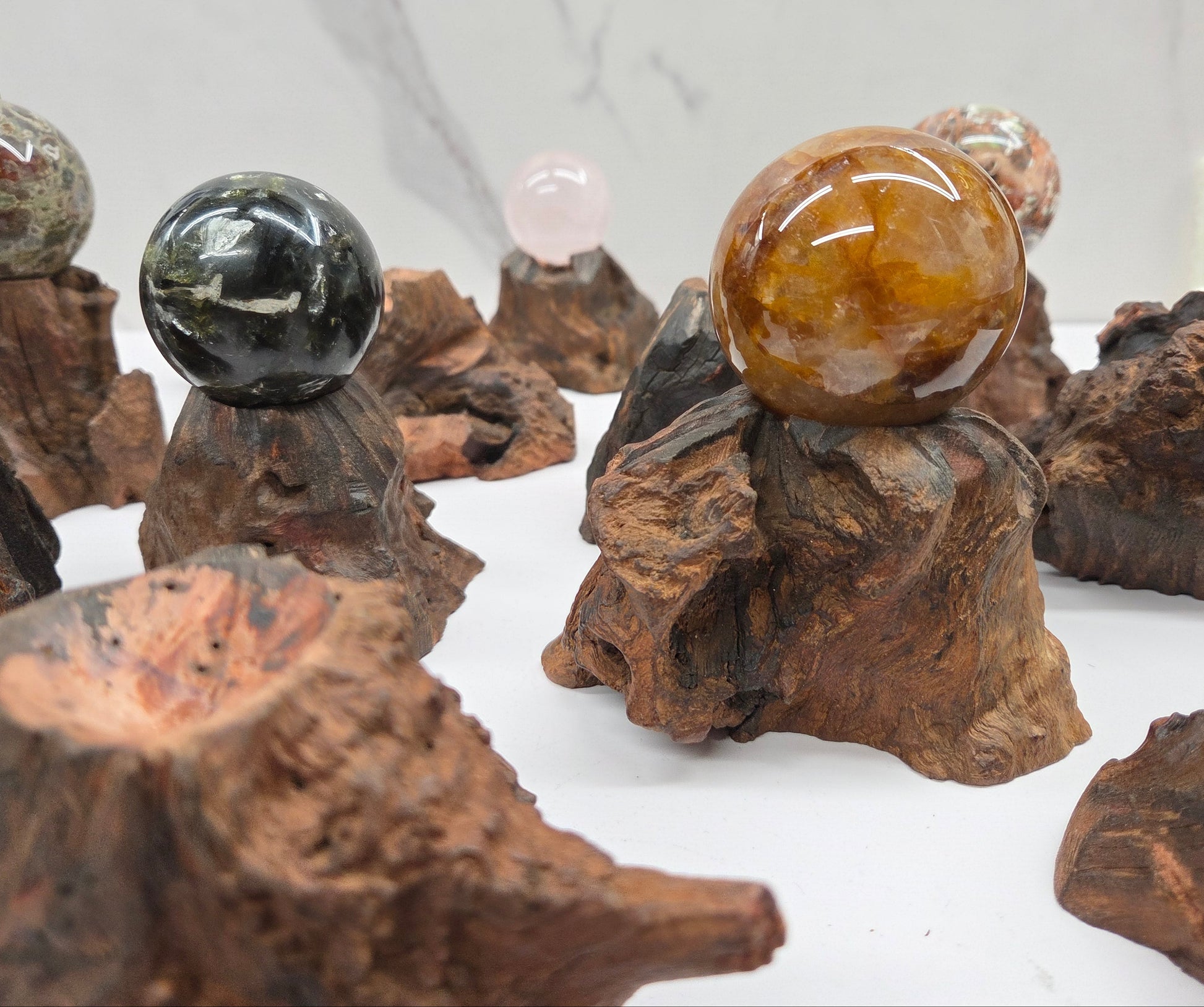 Collection of crystal balls on natural wood bases against a marble background