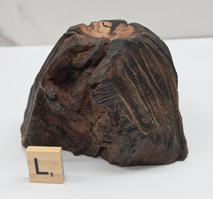 wood sphere holder on a white surface, next to a wooden block with 'L' letter.