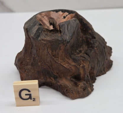 wood sphere holder on a white surface, next to a wooden block with 'G' letter.