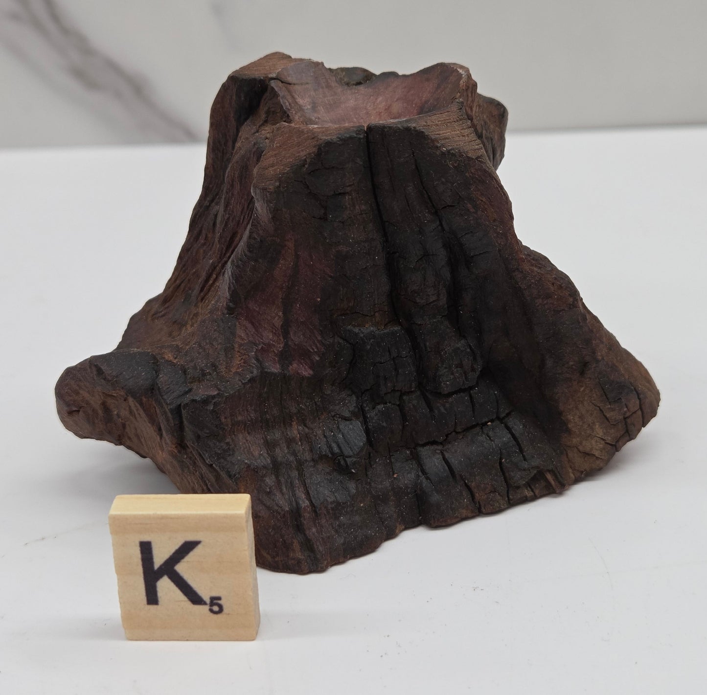 wood sphere holder on a white surface, next to a wooden block with 'K' letter.