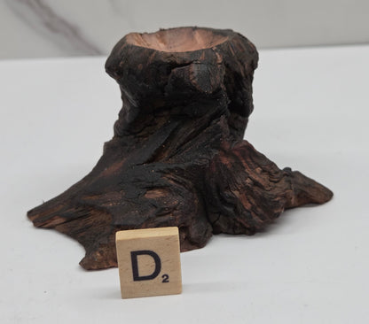 wood sphere holder on a white surface, next to a wooden block with 'D' letter.