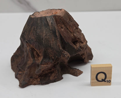 wood sphere holder on a white surface, next to a wooden block with 'Q' letter.