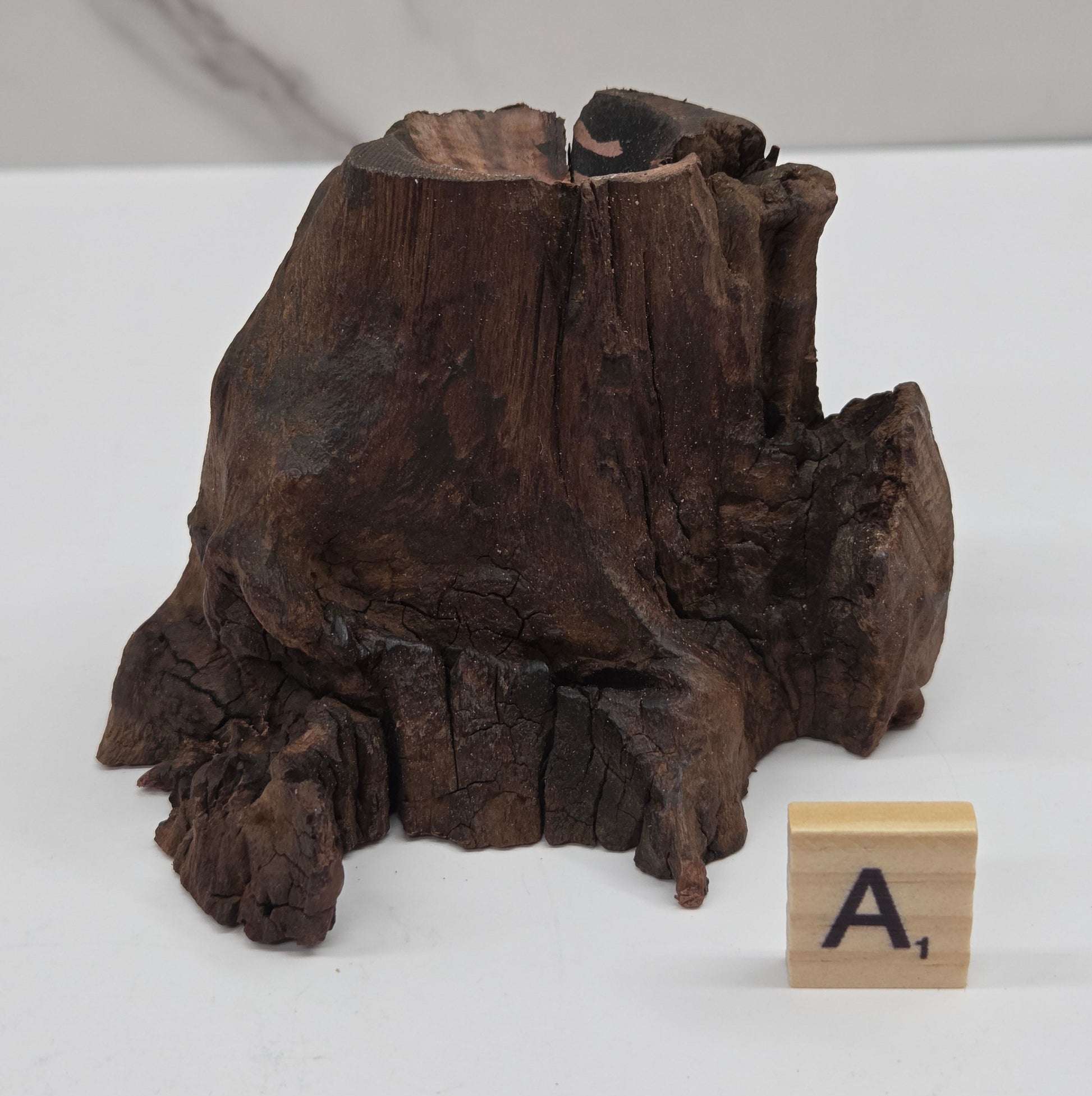 wood sphere holder on a white surface, next to a wooden block with 'L' letter.