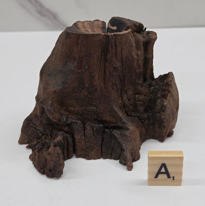 wood sphere holder on a white surface, next to a wooden block with 'L' letter.