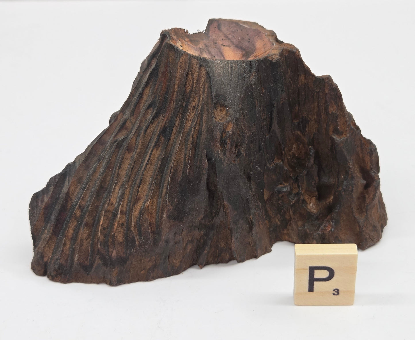 wood sphere holder on a white surface, next to a wooden block with 'P' letter.