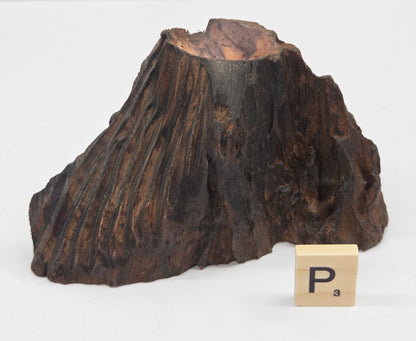 wood sphere holder on a white surface, next to a wooden block with 'P' letter.