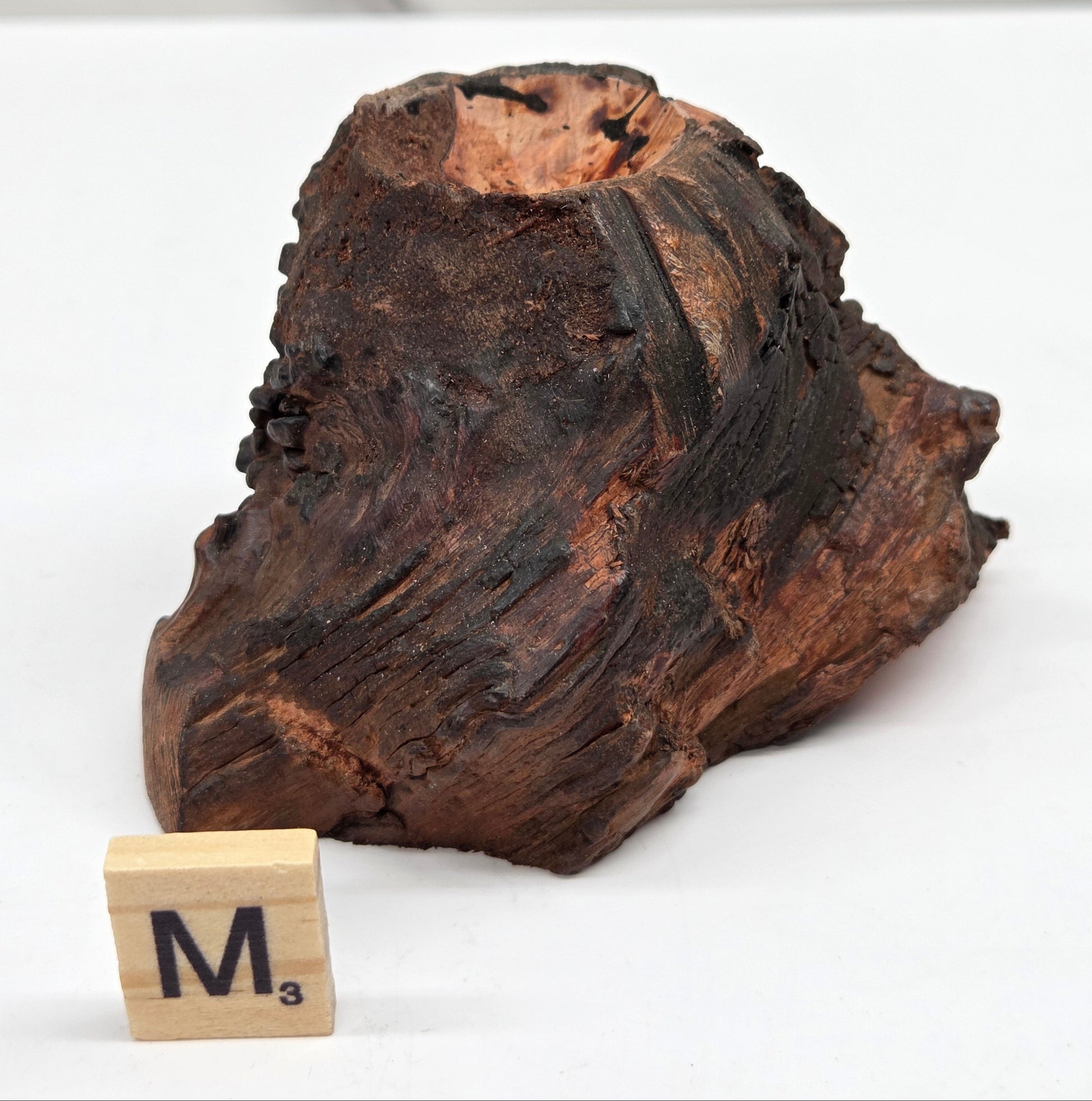 wood sphere holder on a white surface, next to a wooden block with 'M' letter.