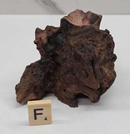 wood sphere holder on a white surface, next to a wooden block with 'F' letter.