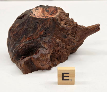 wood sphere holder on a white surface, next to a wooden block with 'E' letter.
