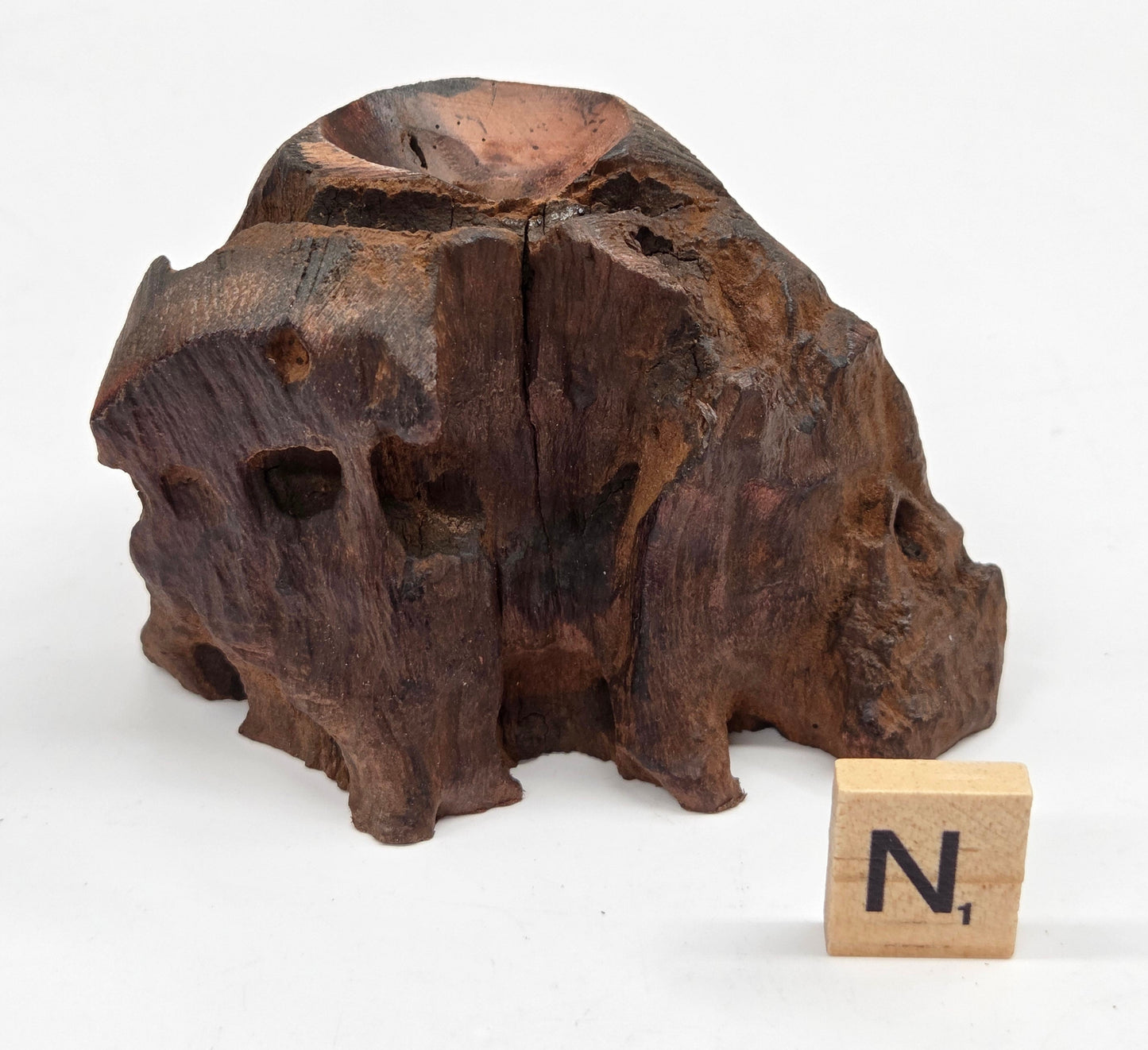 wood sphere holder on a white surface, next to a wooden block with 'N' letter.