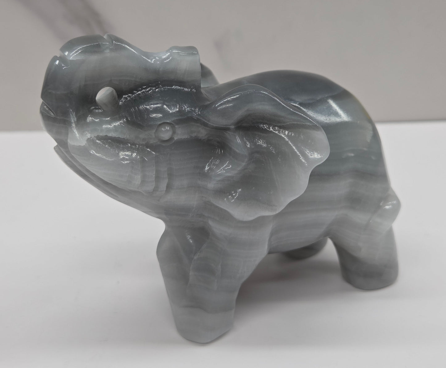 Gray Agate elephant carving on a white surface with a neutral background