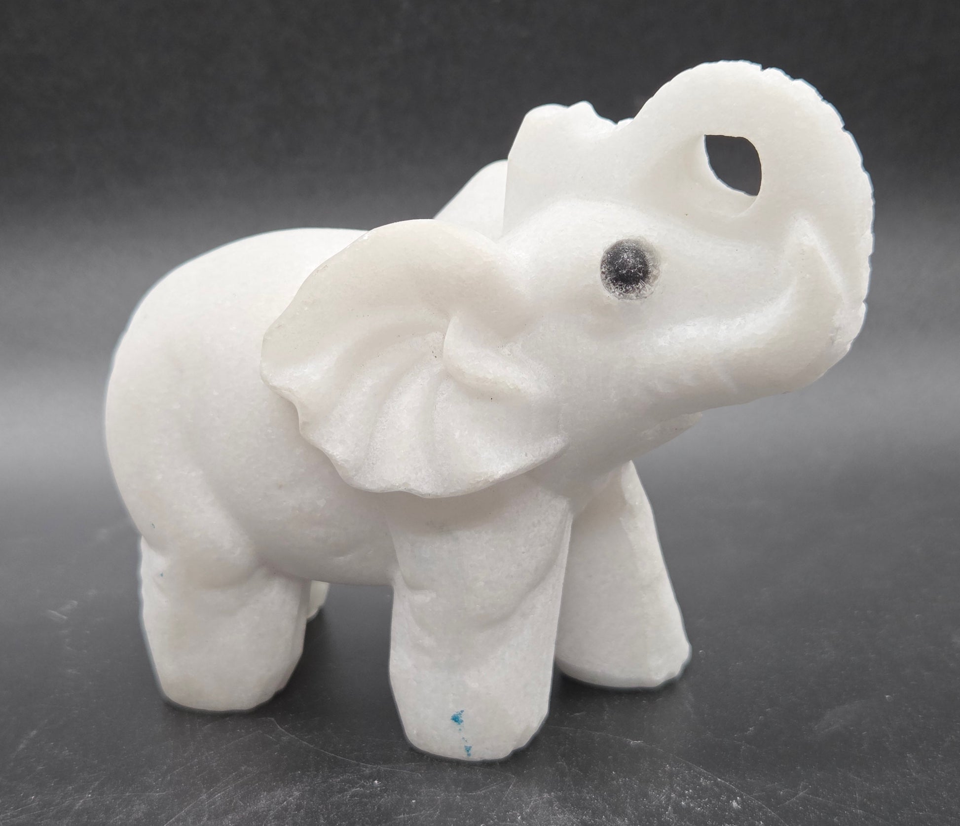 White Jade elephant figurine on a dark gray background