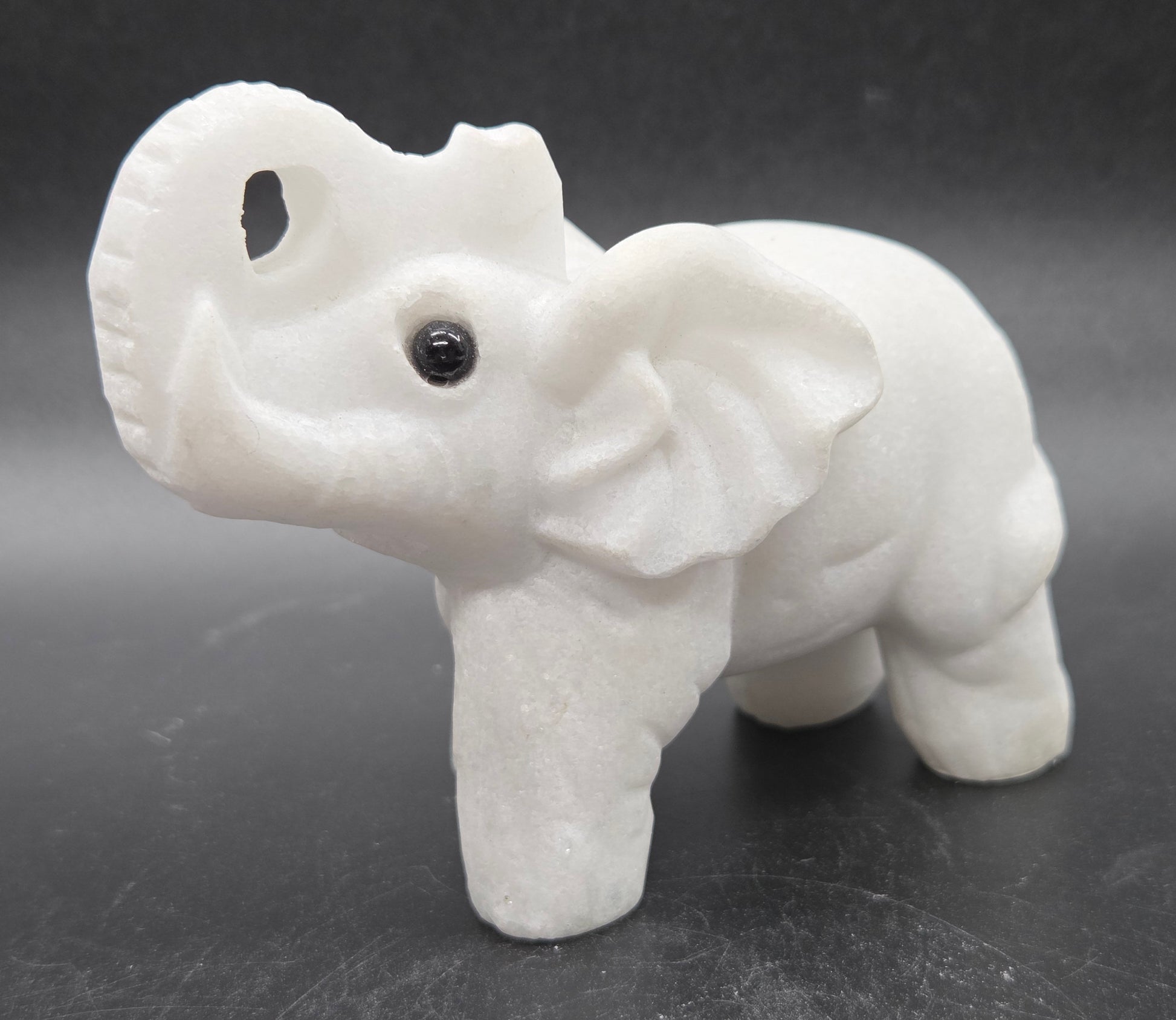 White Jade elephant figurine on a dark gray background