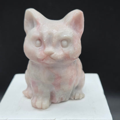 Pink Opal sculpture of a cat on a black background