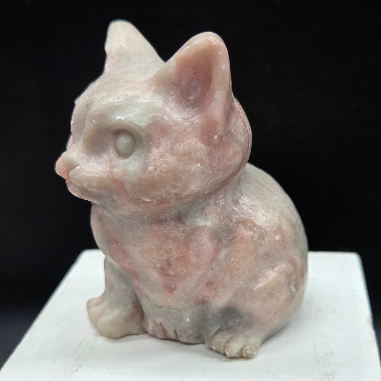 Pink Opal sculpture of a cat on a black background