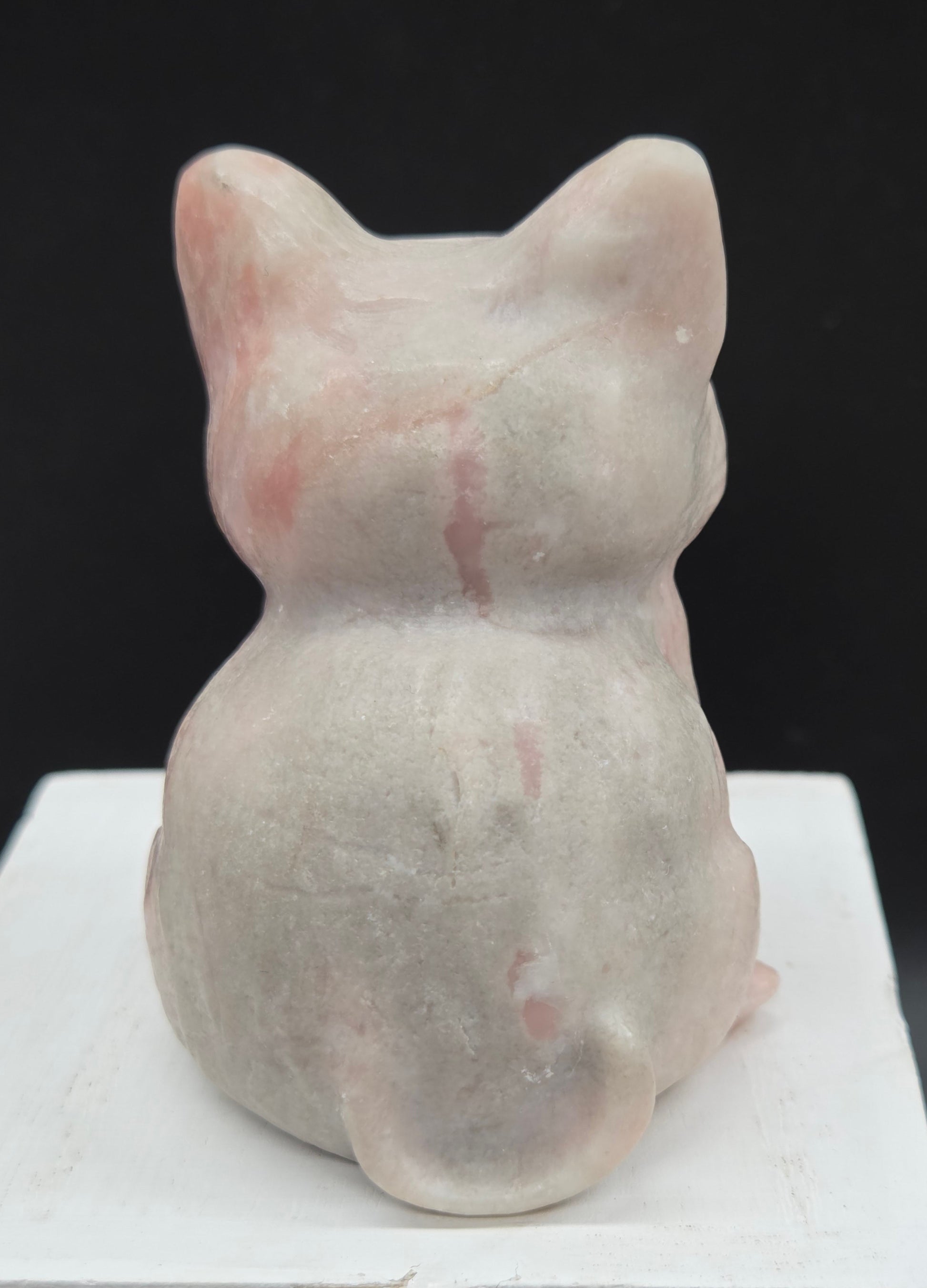 Pink Opal sculpture of a cat on a black background