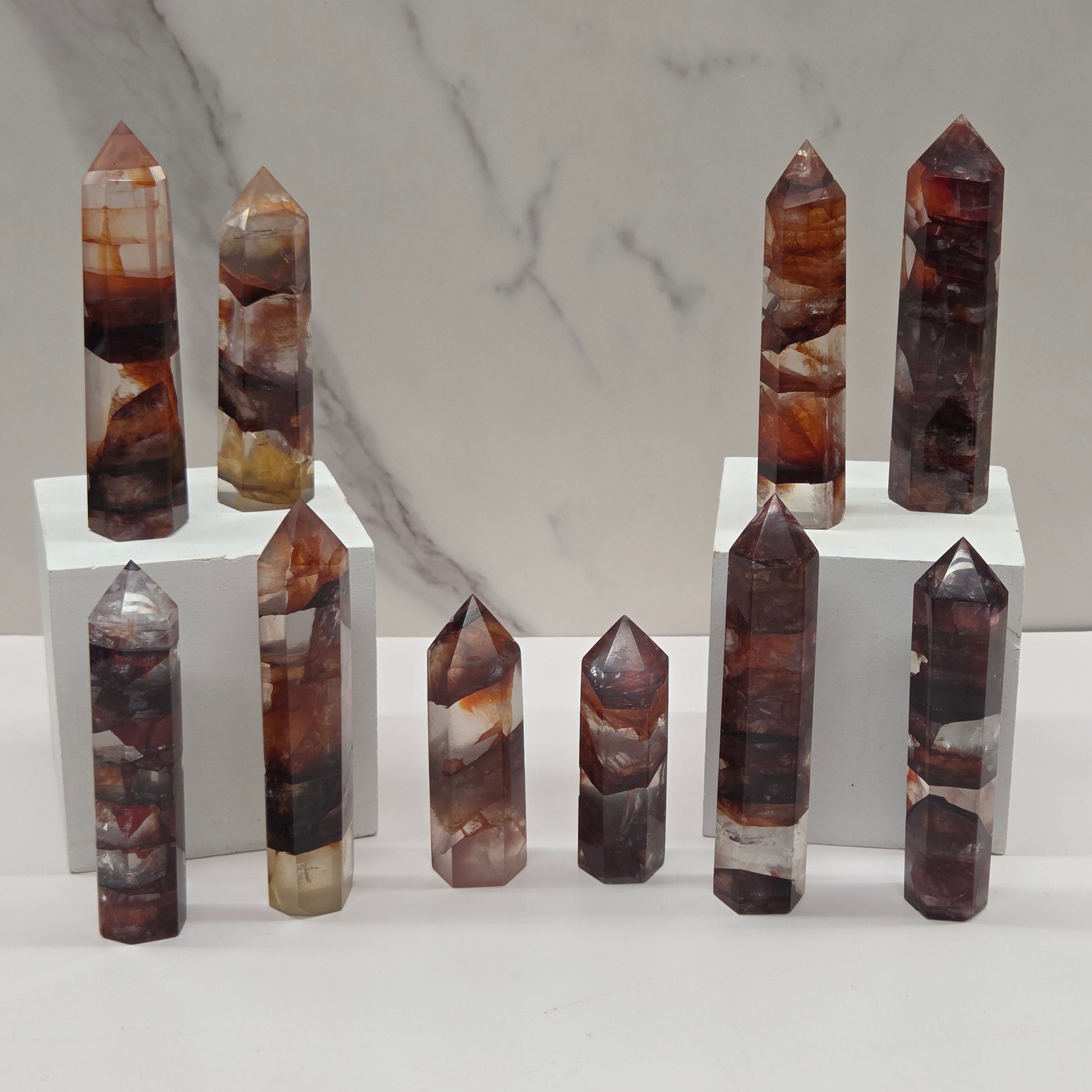 Set of fire quartz crystal points on a white stand against a marble background