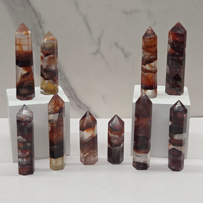 Set of fire quartz crystal points on a white stand against a marble background