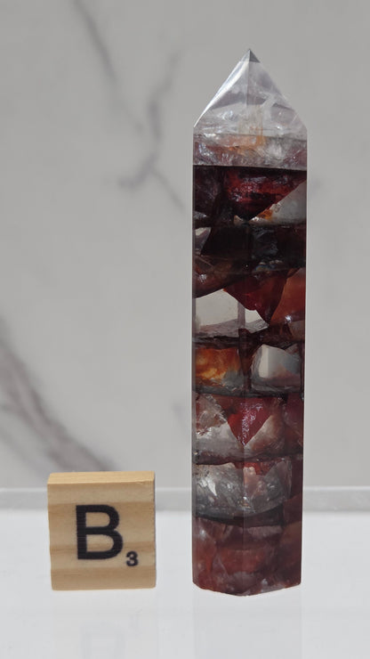 fire quartz crystal point on a white stand against a marble background