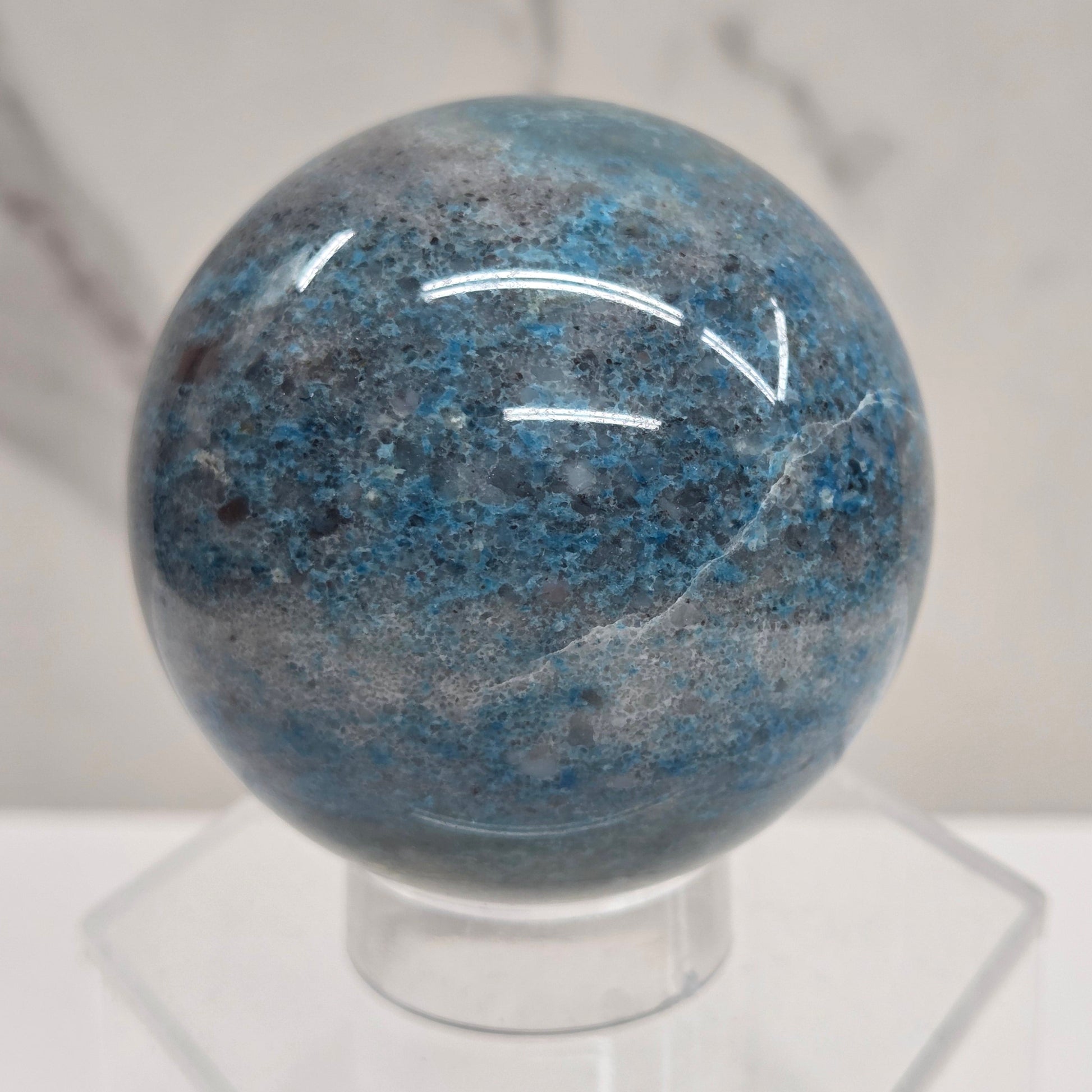 Trolleite sphere with blue and black colors on an acrylic stand against a white background
