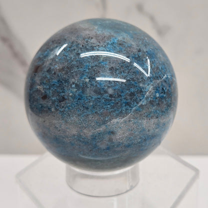 Trolleite sphere with blue and black colors on an acrylic stand against a white background