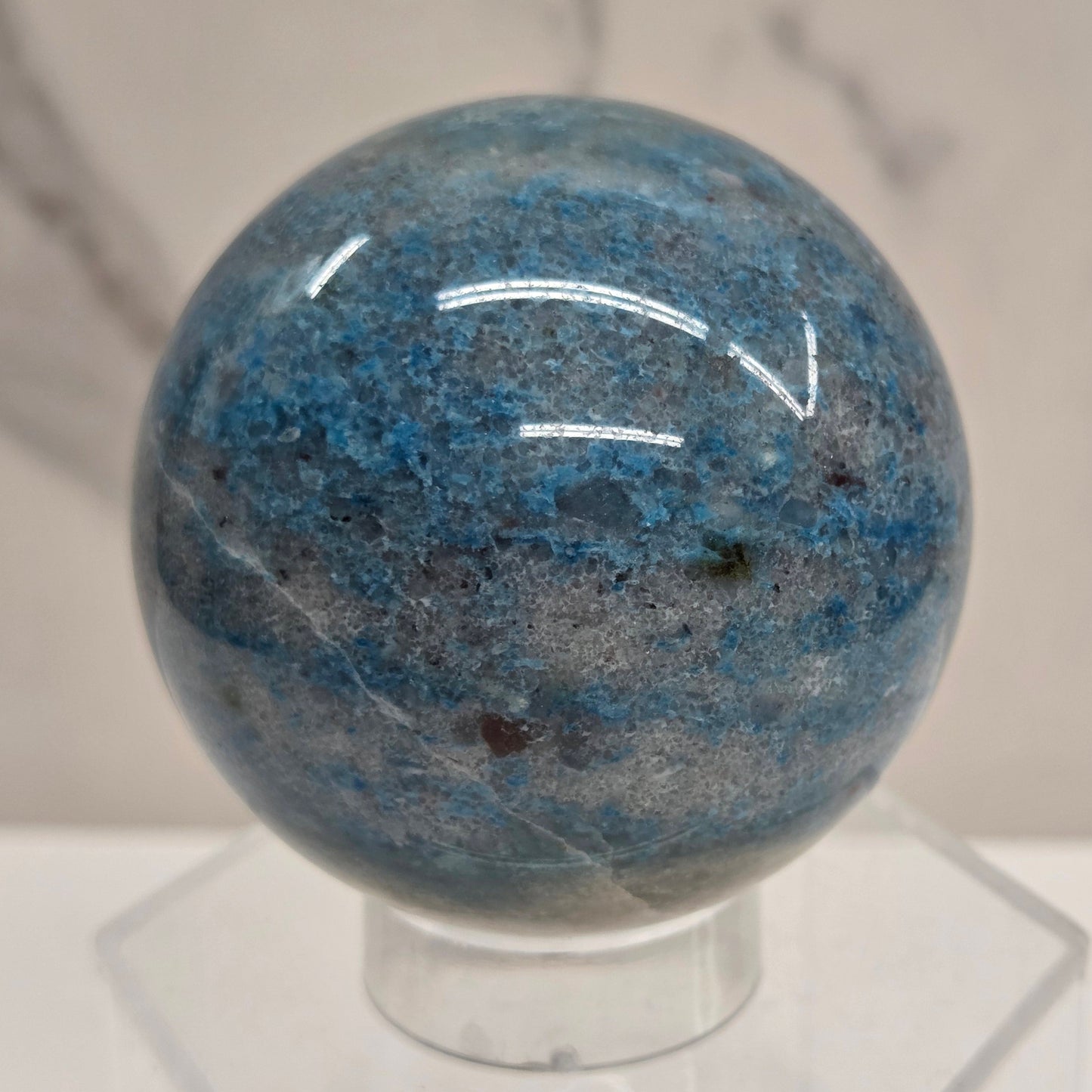 Trolleite sphere with blue and black colors on an acrylic stand against a white background