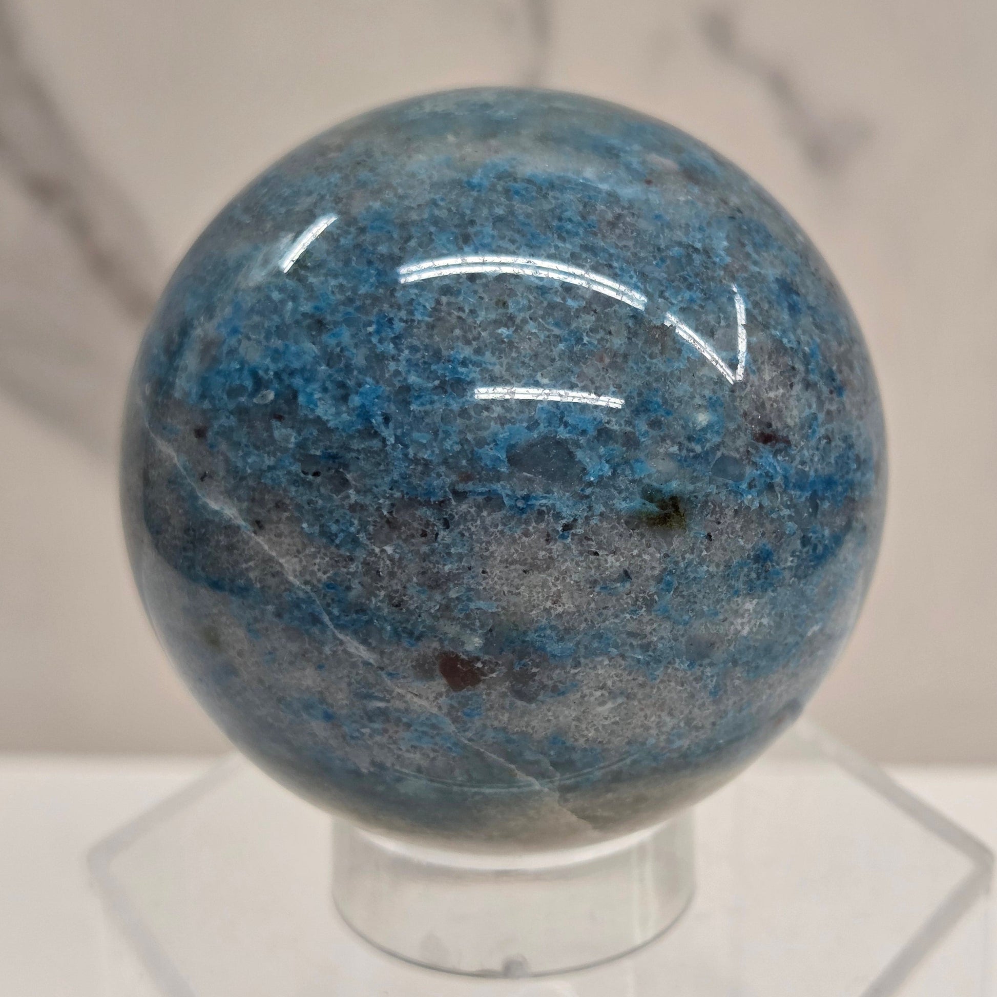 Trolleite sphere with blue and black colors on an acrylic stand against a white background
