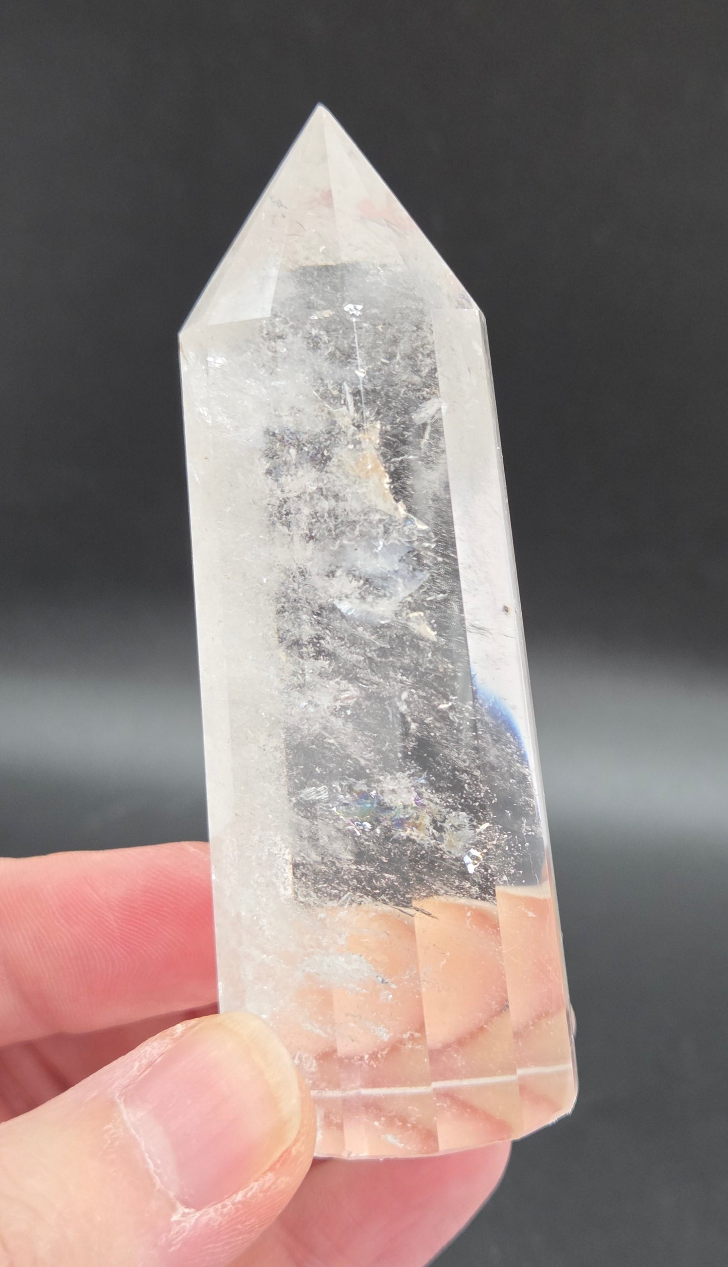 Crystal point held by a hand against a dark background
