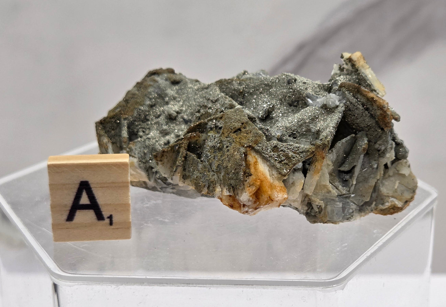 Mineral sample with a clear acrylic stand on a light gray background