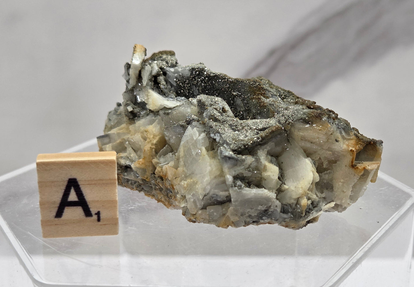 Mineral sample on a stand with a wooden block labeled 'A1' against a light background