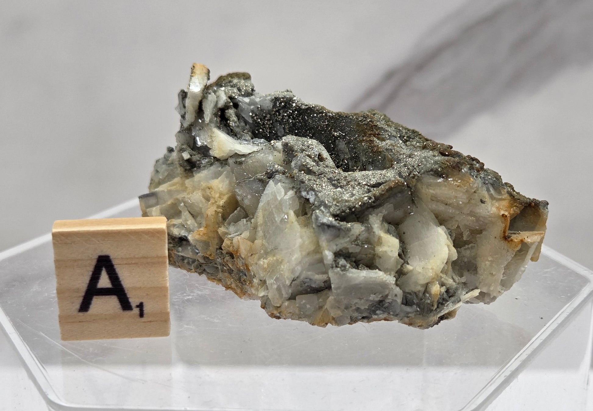 Mineral sample on a stand with a wooden block labeled 'A1' against a light background