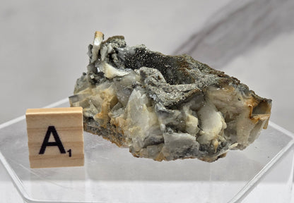 Mineral sample on a stand with a wooden block labeled 'A1' against a light background