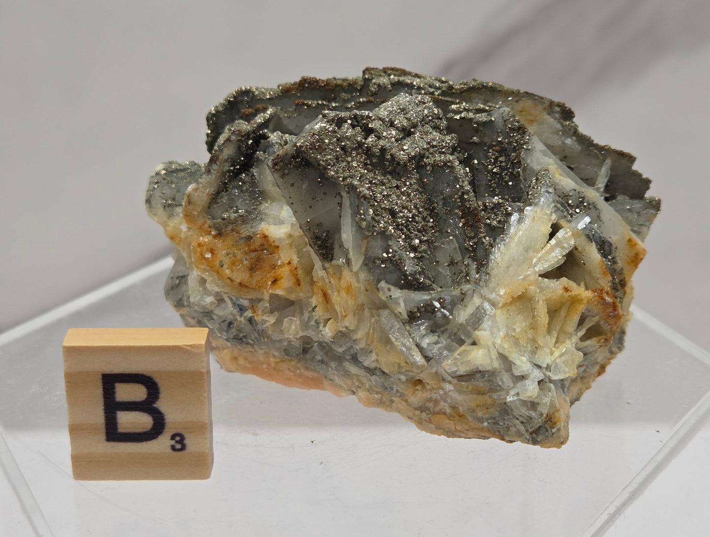 Mineral sample on a clear stand with a wooden label on a white background