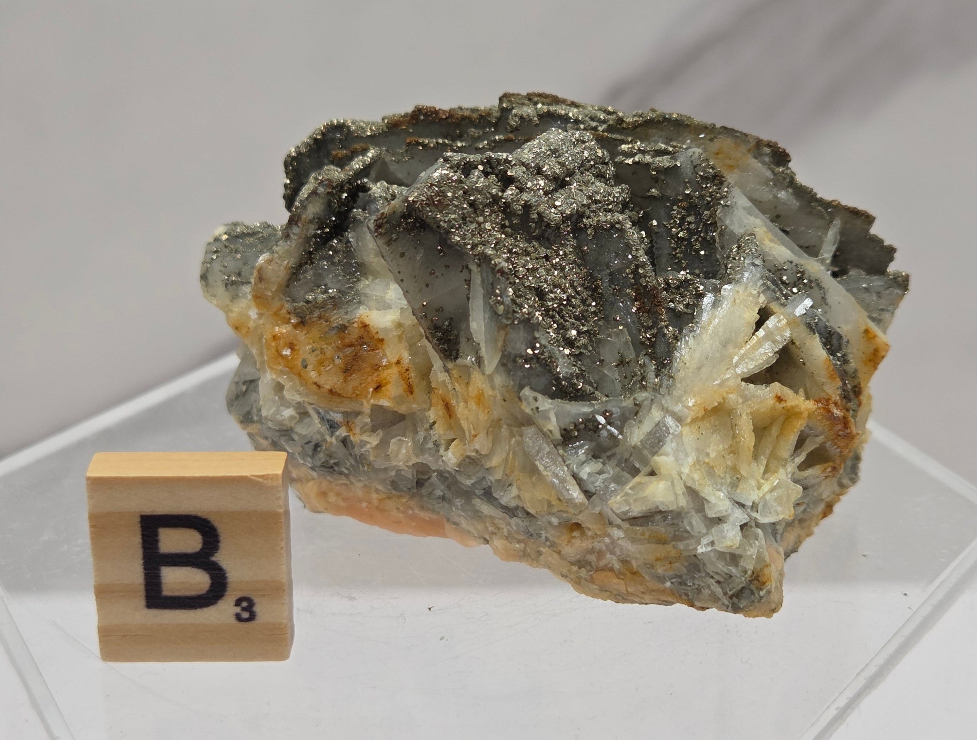 Mineral sample on a clear stand with a wooden label on a white background